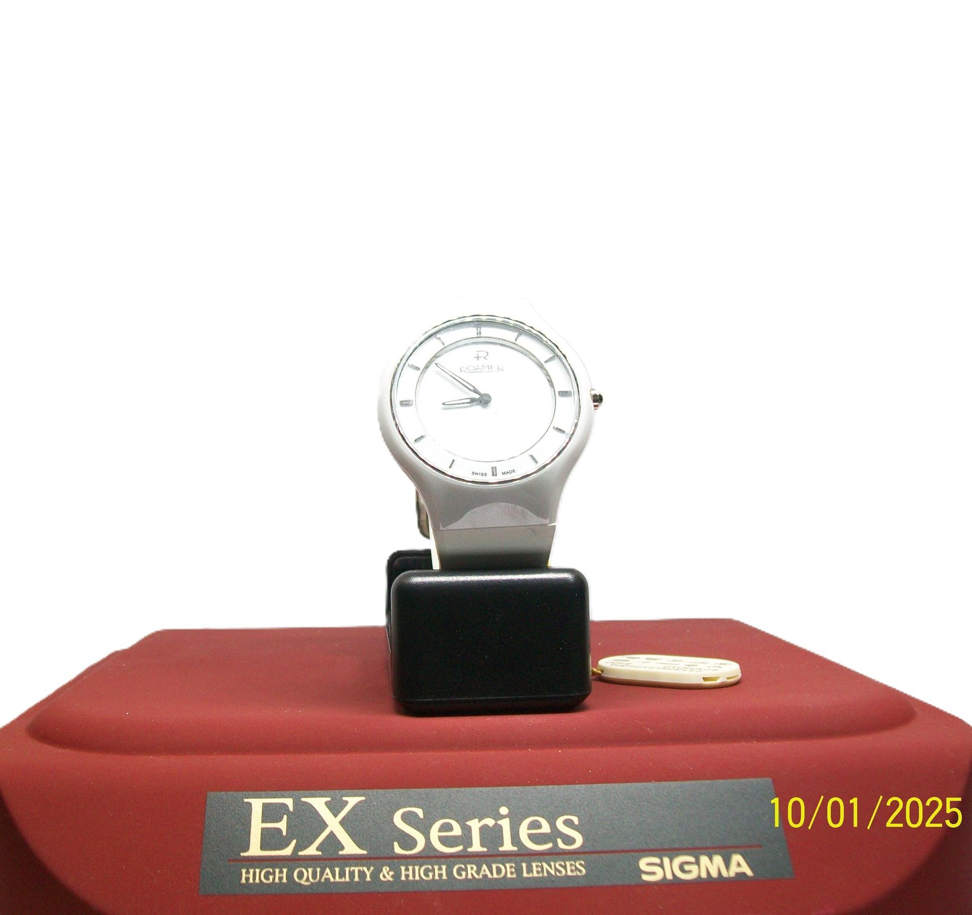 Een hoogwaardige meter uit de Sigma EX-serie op een rode displayvoet met een zwart blok en een witte achtergrond.