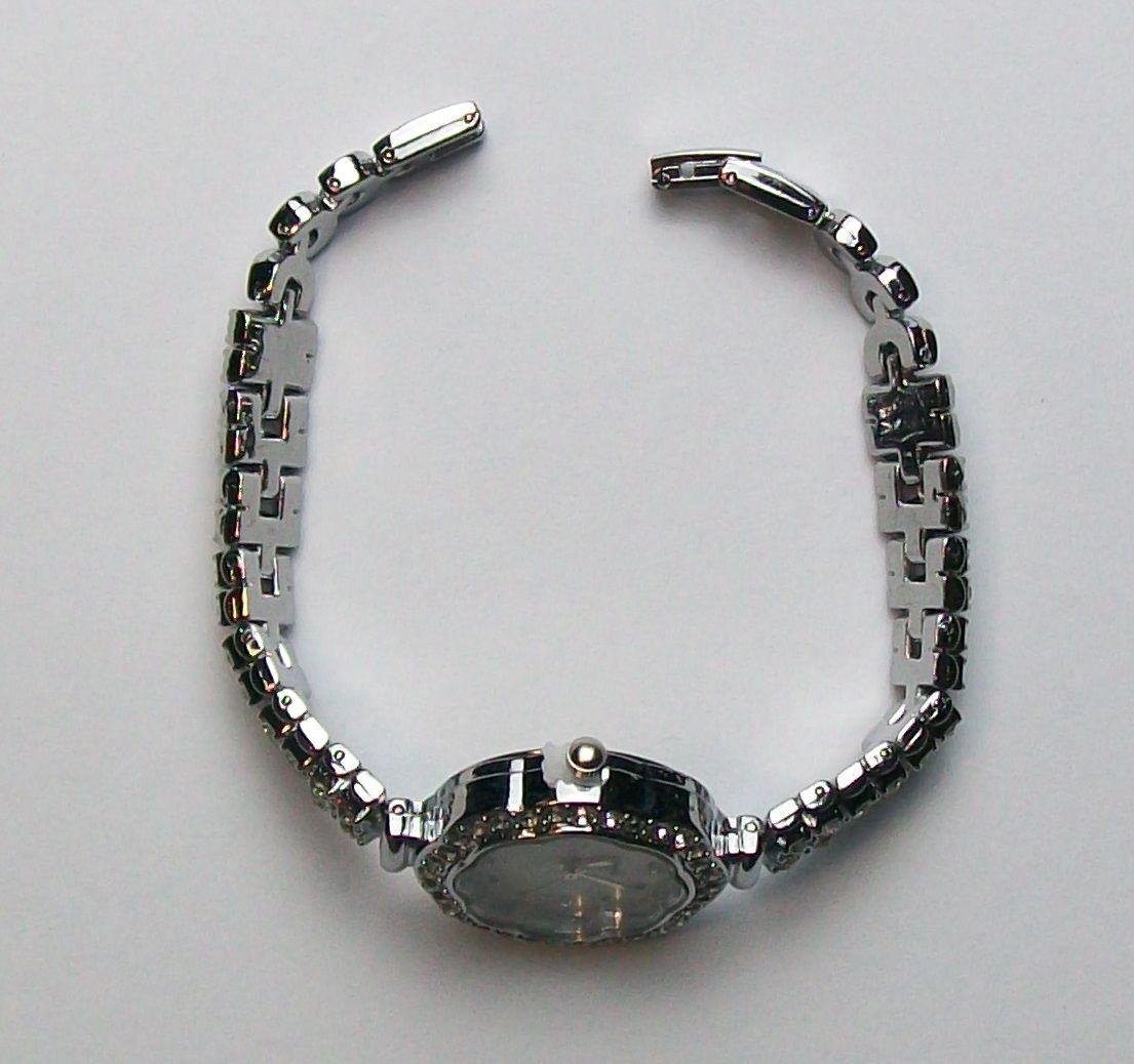 Zilveren polshorloge met witte wijzerplaat, kristallen lunette en kristallen uurmarkeringen.