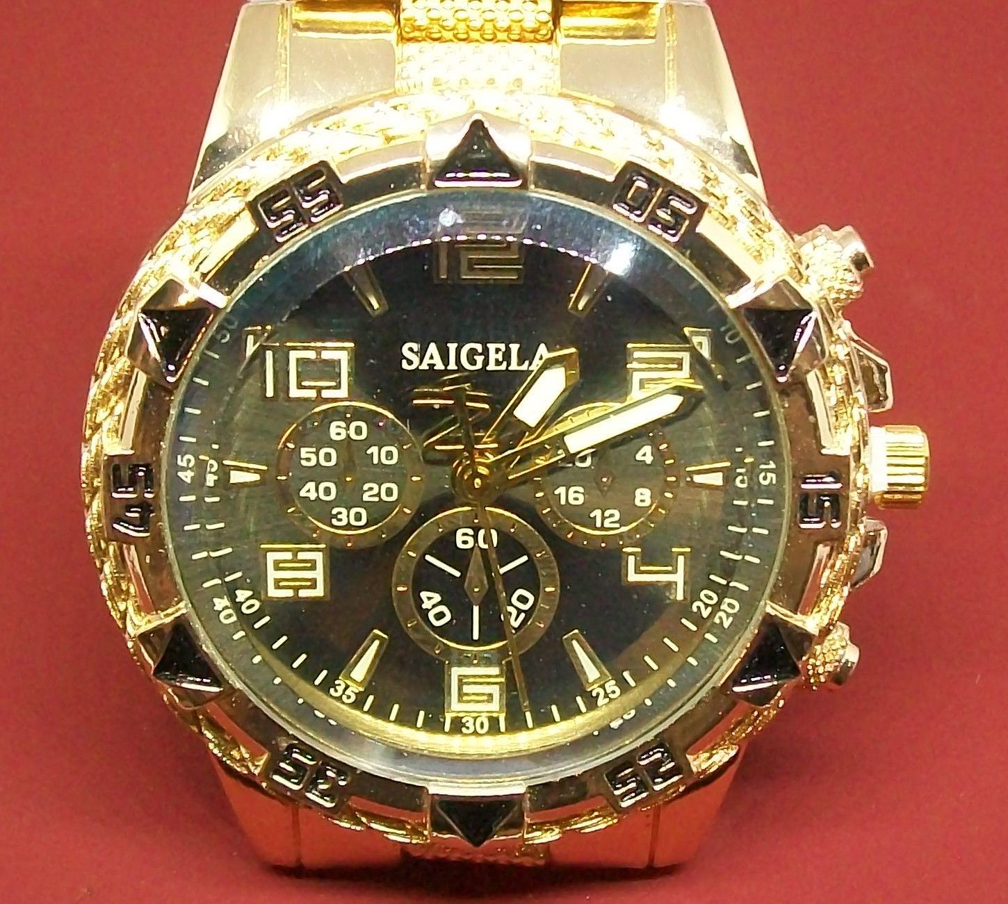 Gouden polshorloge met zwarte wijzerplaat en gouden wijzers en markeringen. Het horloge heeft een getextureerde band.