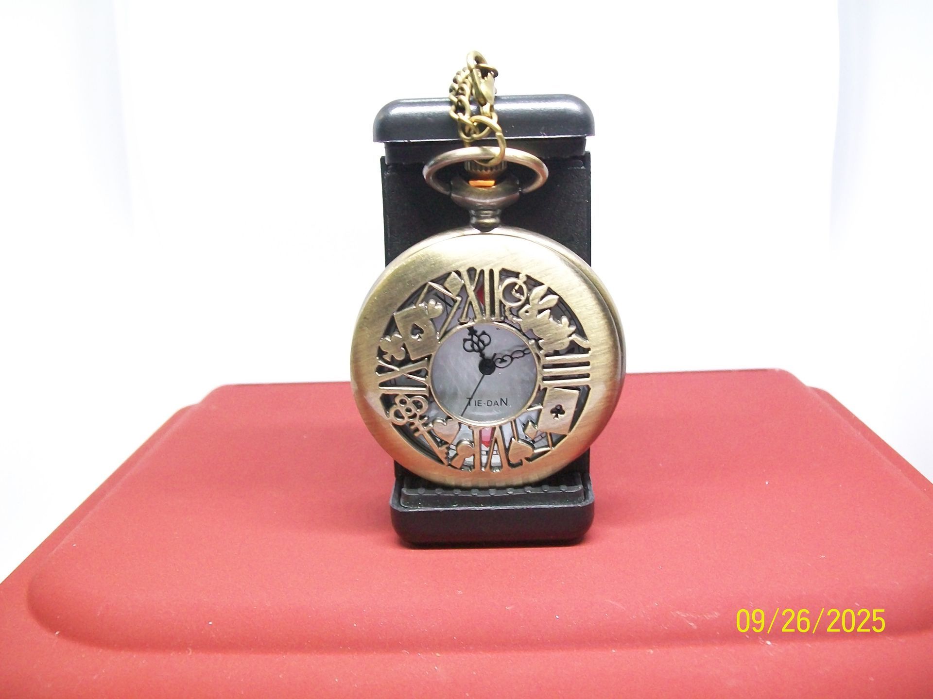 Zakhorloge met speelkaartsymbolen op een witte wijzerplaat, open op een rode ondergrond.