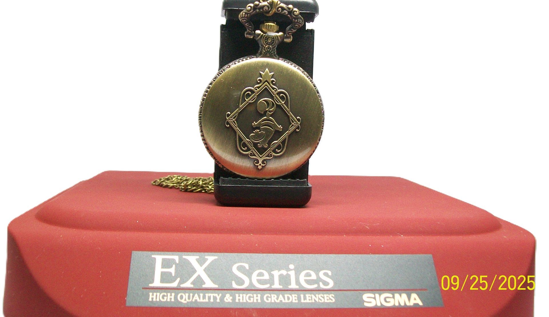 Antiek zakhorloge met open wijzerplaat op een rood oppervlak, met wijzers op 1:14.