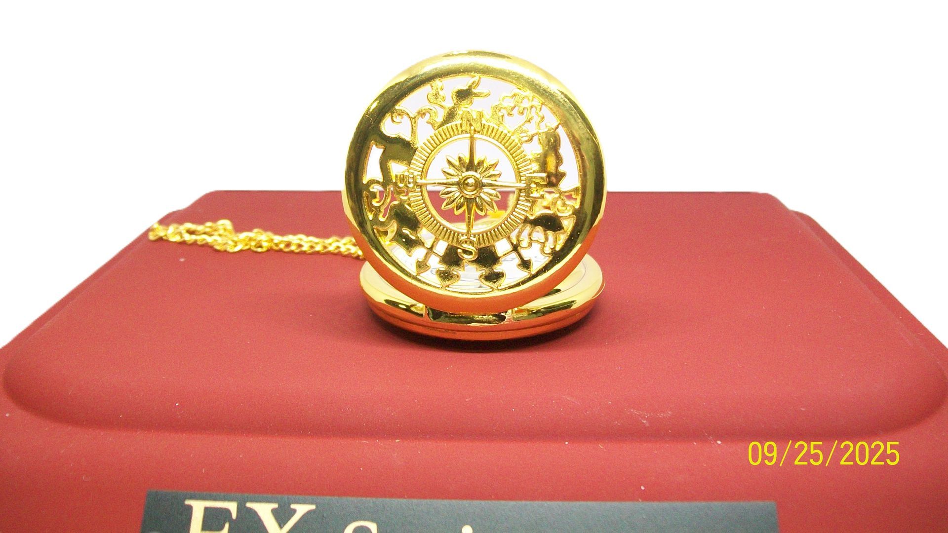 Gouden zakhorloge op een rood platform, zwarte standaard. 