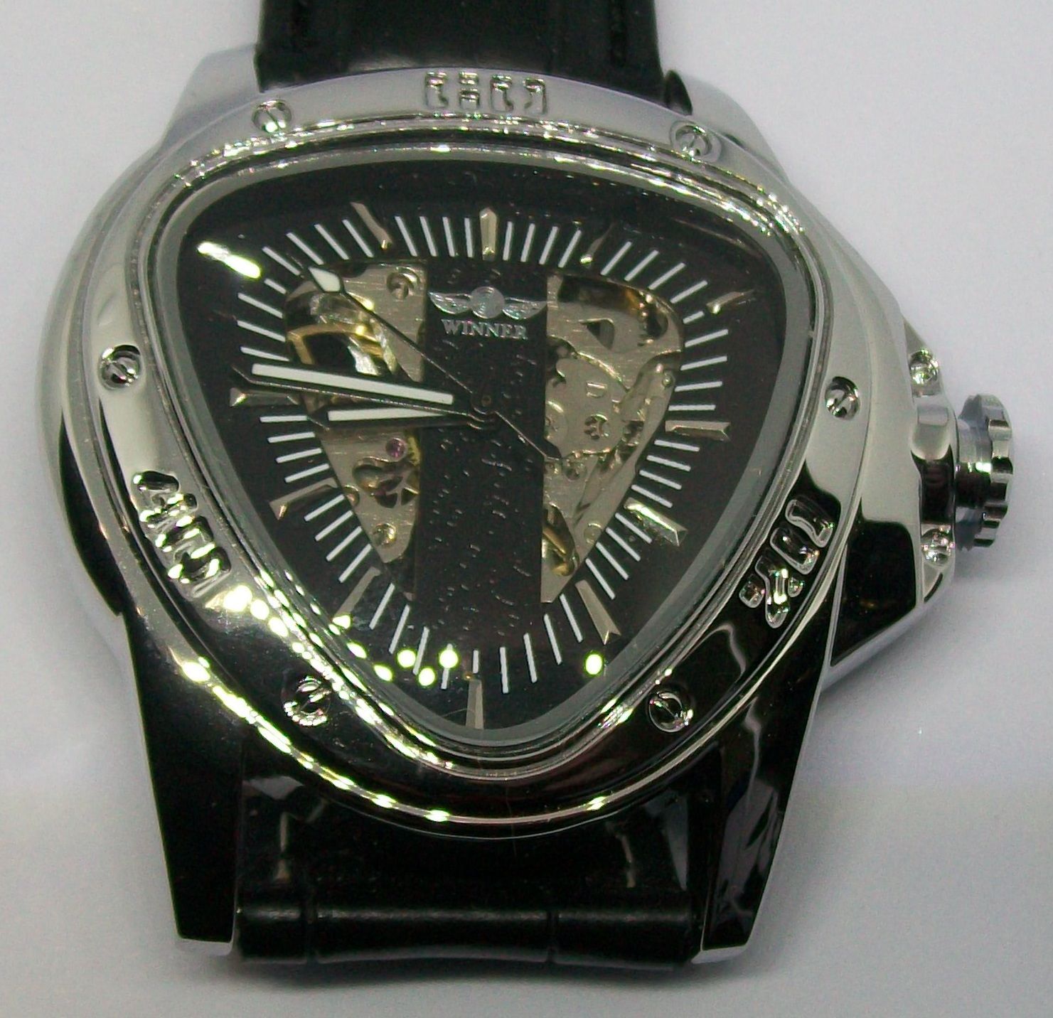 Zilverkleurig en zwart driehoekig Winner herenhorloge met skeletkleurige wijzerplaat en zwarte leren band.
