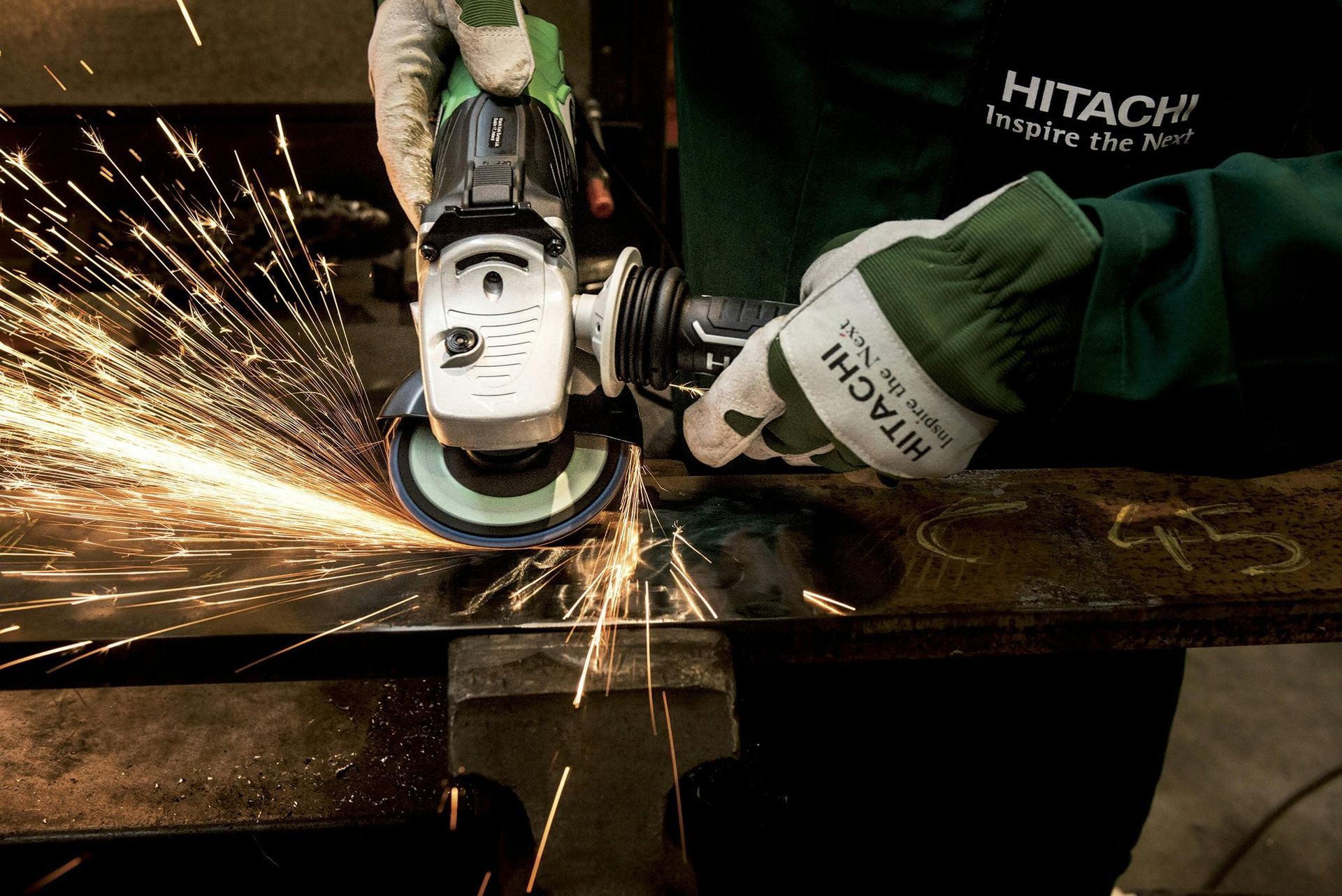 Een persoon in een werkplaats gebruikt een haakse slijper van Hitachi en veroorzaakt vonken op metaal.