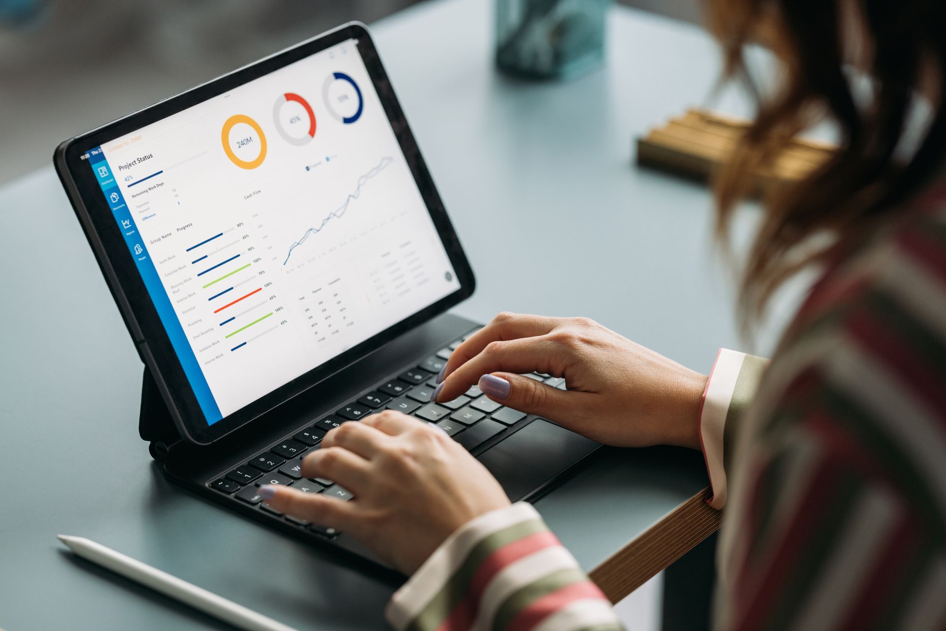 Woman using tablet with keyboard, viewing data visualizations.