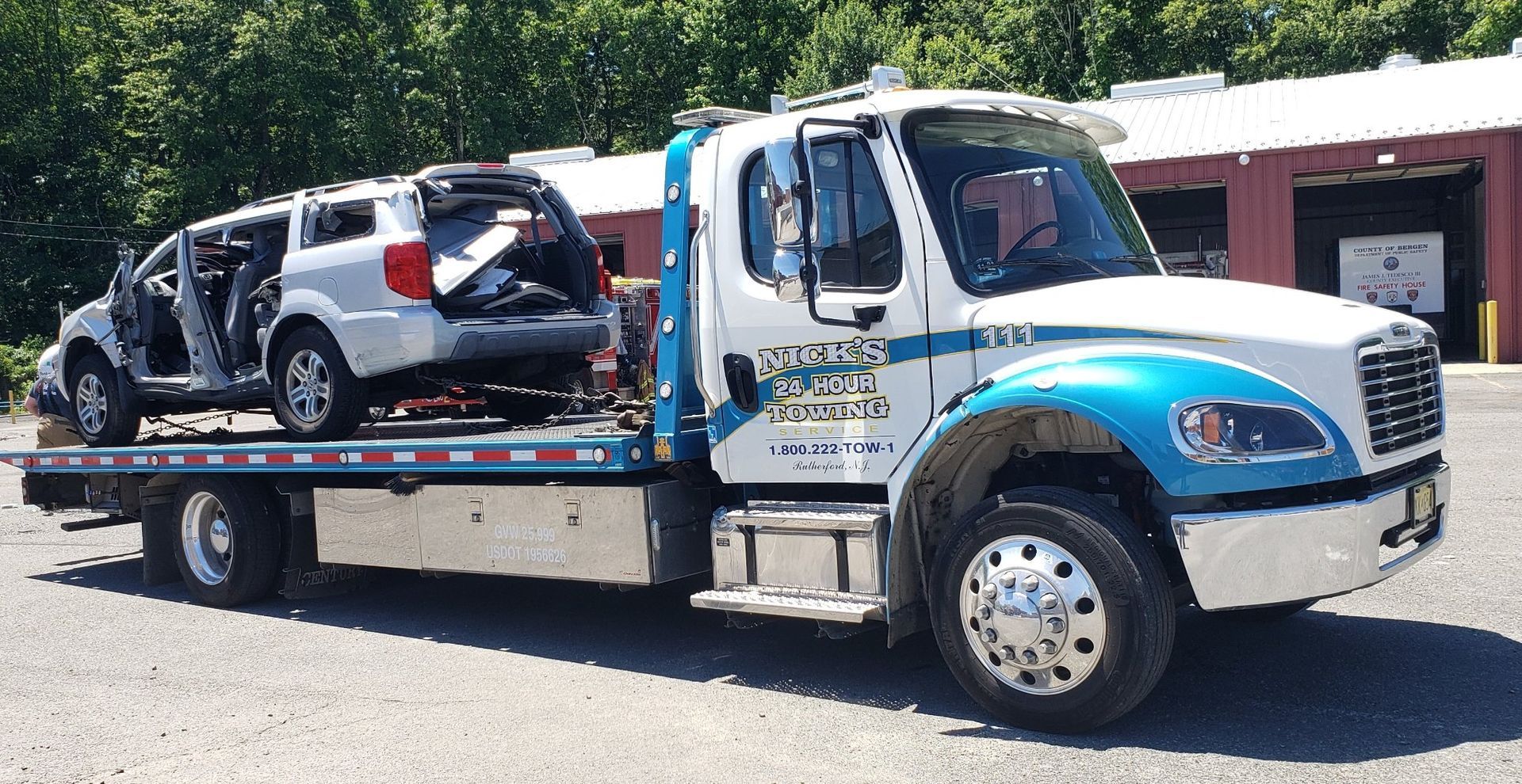 Nick’s 24 Hour Towing flatbed hauling a severely damaged SUV in Bergen County NJ for emergency recovery service.