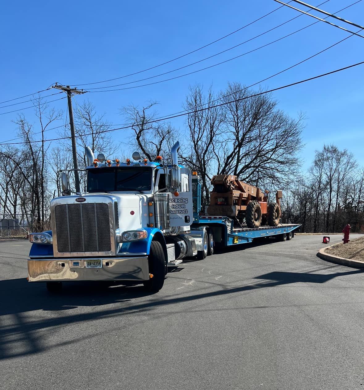 Nick’s Towing hauling heavy equipment in Wallington NJ with flatbed transport truck.