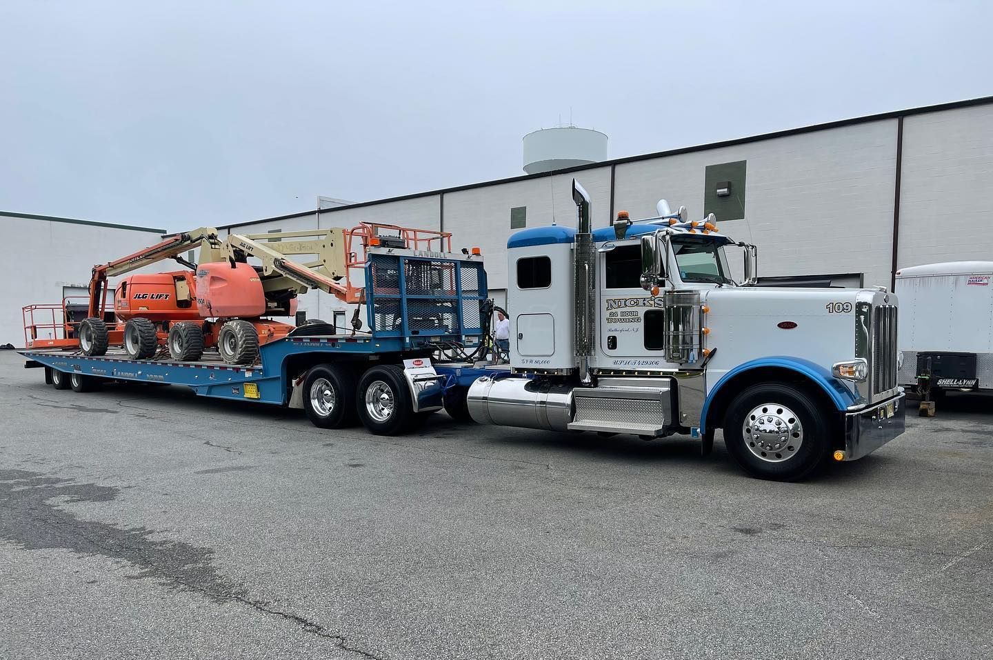 Nick’s Towing in Wallington NJ hauling boom lifts with flatbed truck—expert heavy equipment transport.