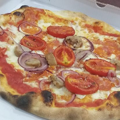 Una pizza con pomodori e cipolle sopra è in una scatola