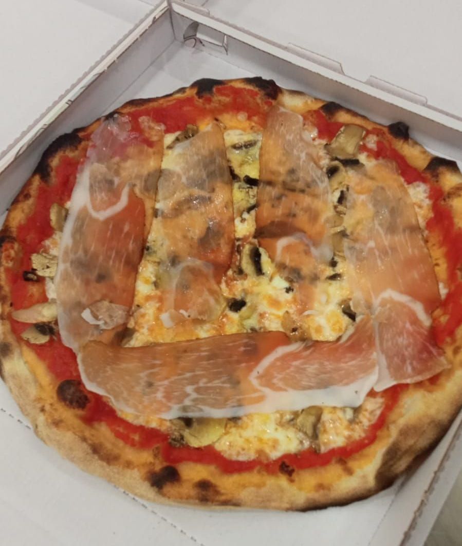 Una pizza con tanti condimenti è in una scatola