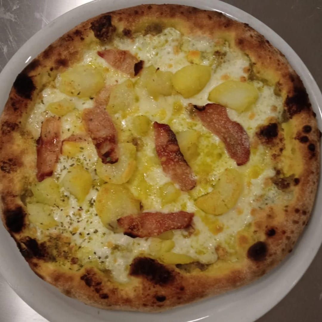 Una pizza con ananas e pancetta su un piatto bianco