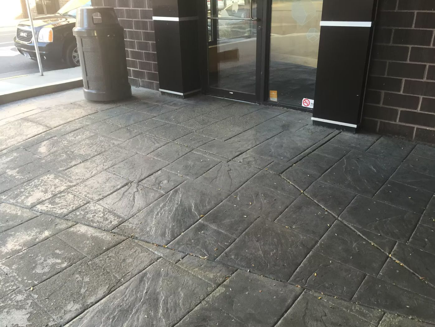 Dark gray textured concrete sidewalk in front of a building with a door.