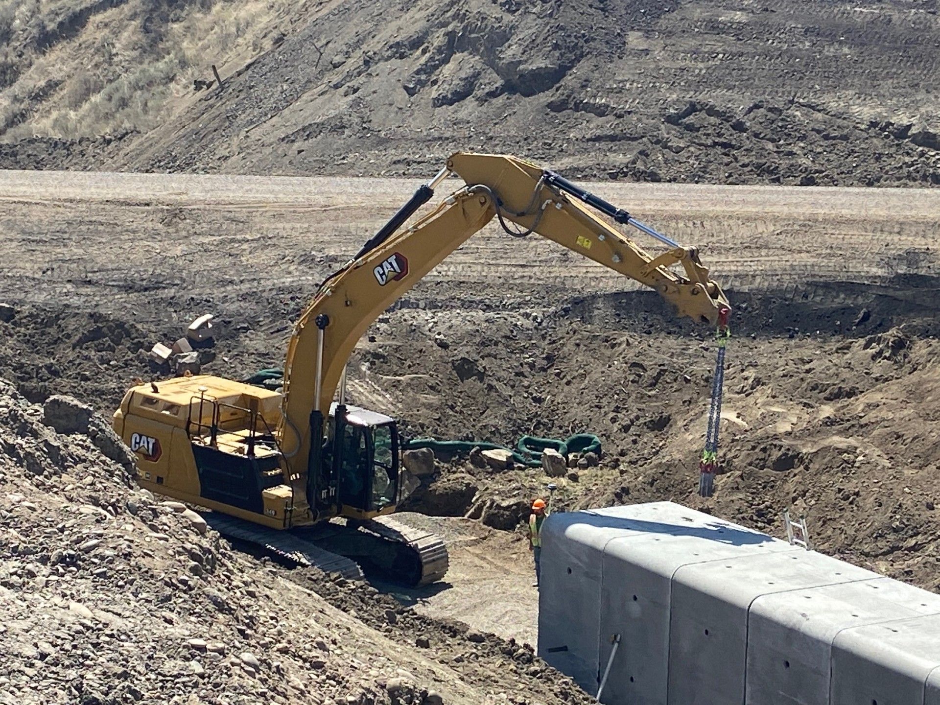 Yellow excavator digging in dirt at construction site.