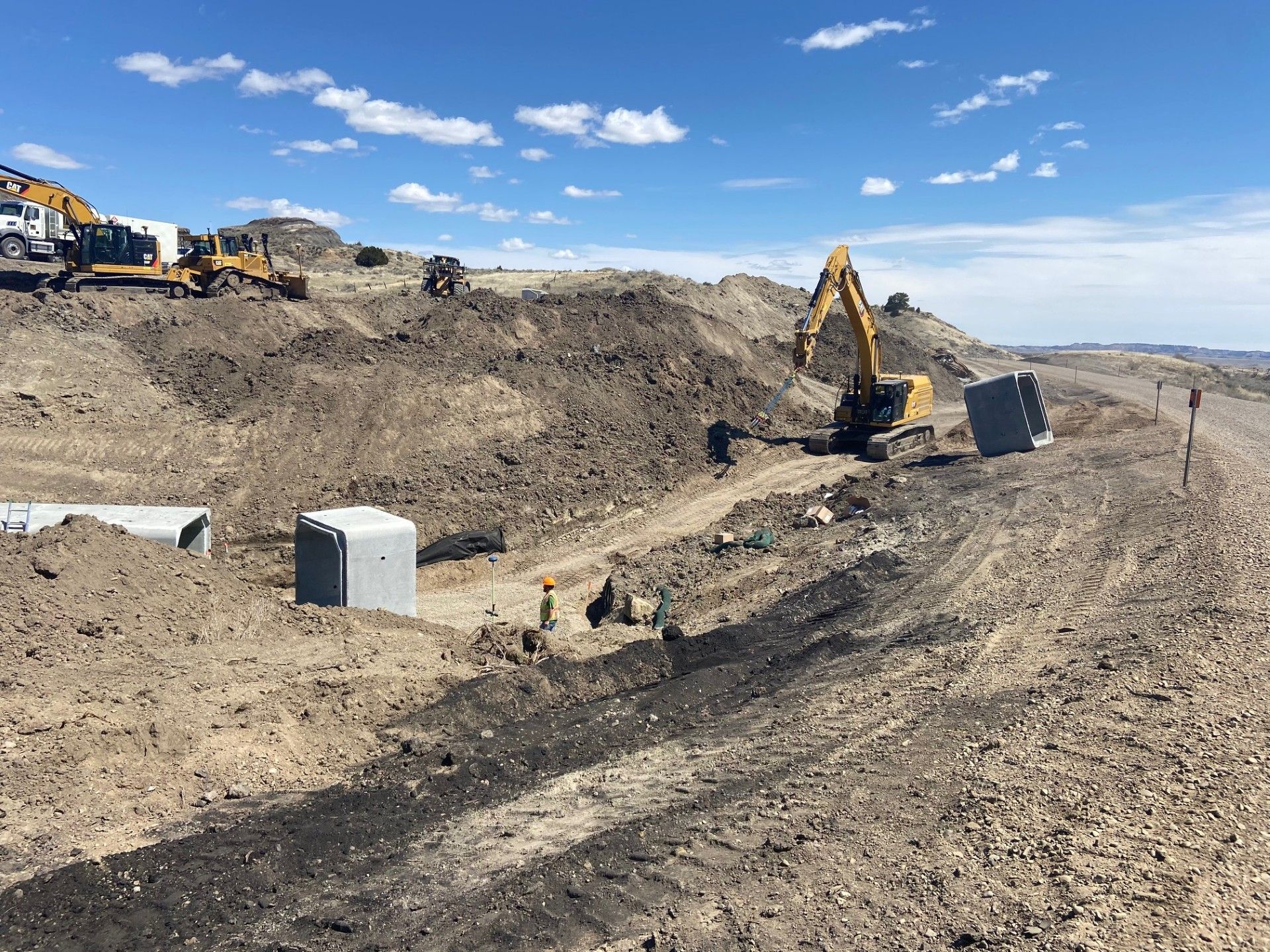 Construction site with excavators and workers moving earth and installing concrete structures.