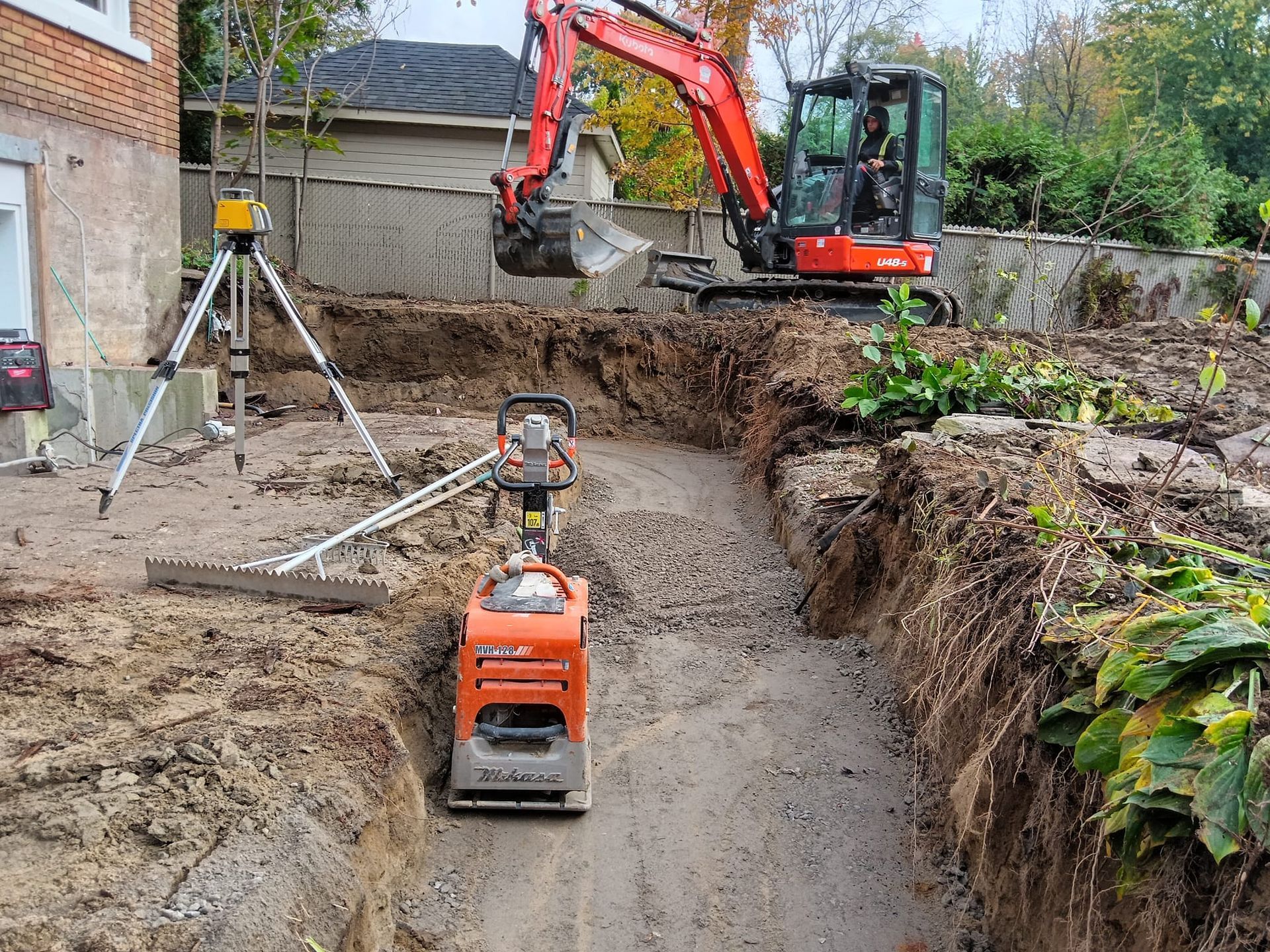 Une excavatrice rouge creuse un trou dans le sol.