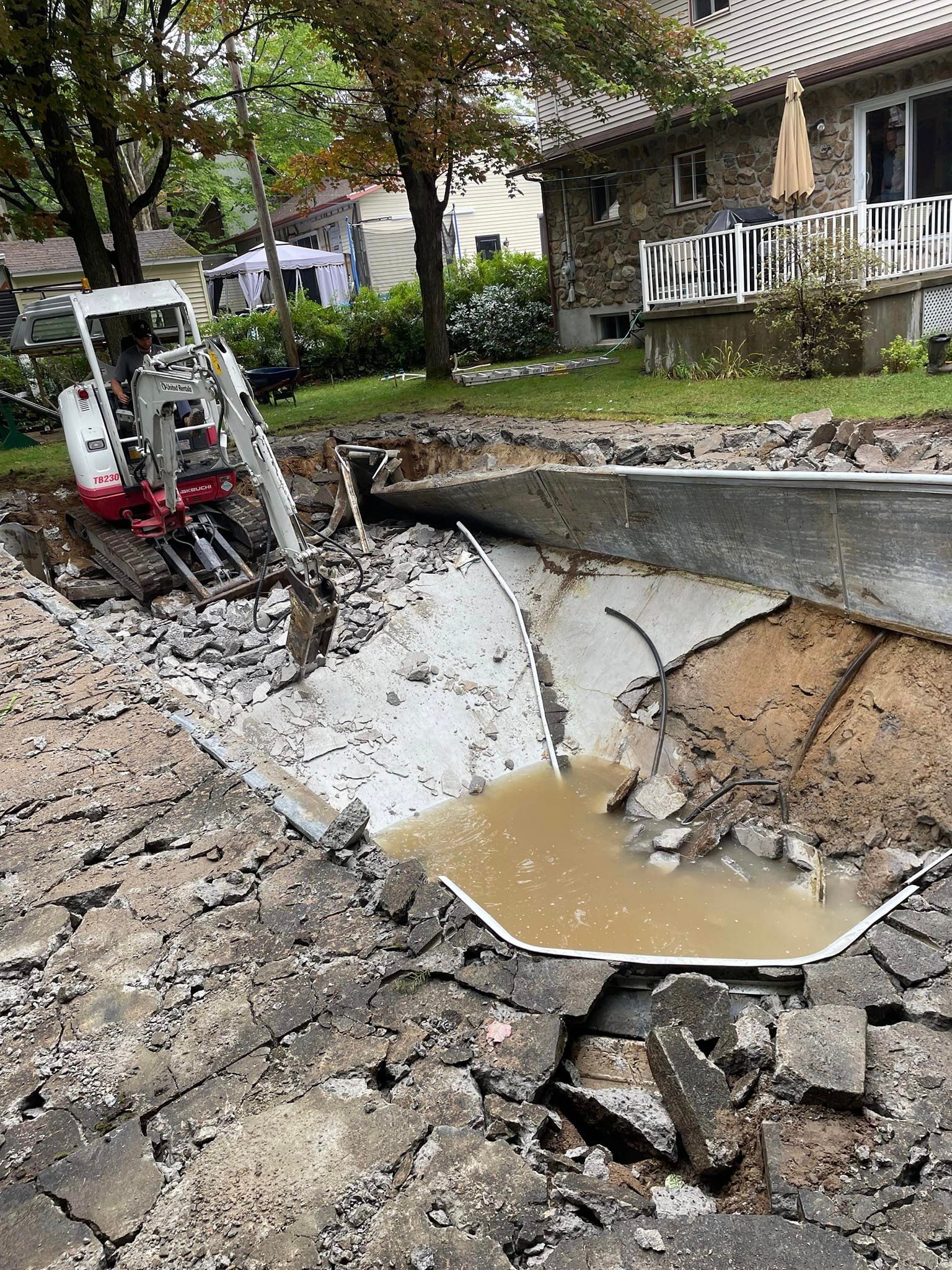 Un bulldozer creuse un trou dans le sol devant une maison.