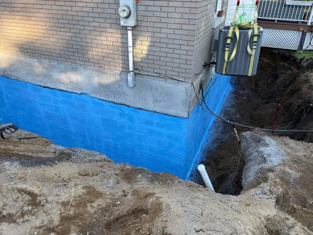Une barrière bleue est en cours d'installation sur le côté d'un bâtiment en brique.