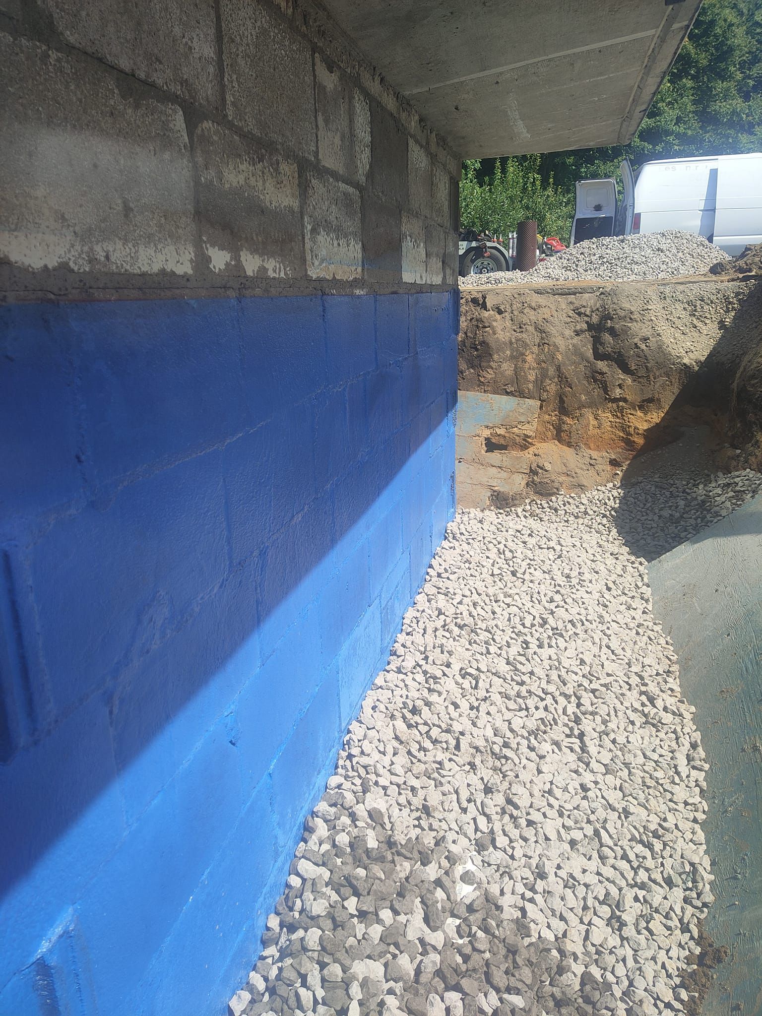 Une barrière bleue se trouve au sommet d'un tas de gravier à côté d'un mur de briques.