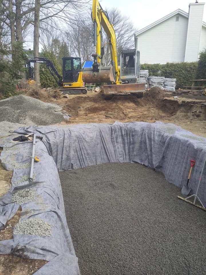 Une excavatrice jaune creuse un trou dans le sol devant une maison.