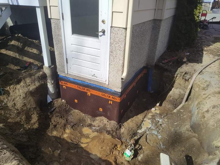 Une porte blanche est posée dans la terre à côté d'une maison.