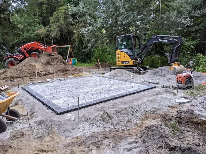 Une petite excavatrice est posée sur un tas de terre à côté d'une brouette.