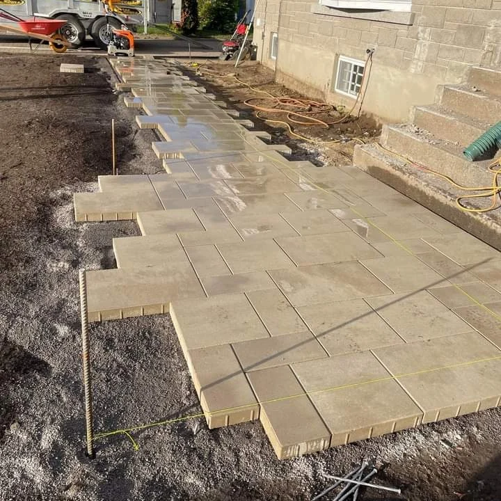 Une passerelle en brique est en cours de construction devant une maison.