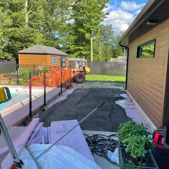 Un tracteur roule sur un chemin de terre devant une maison.