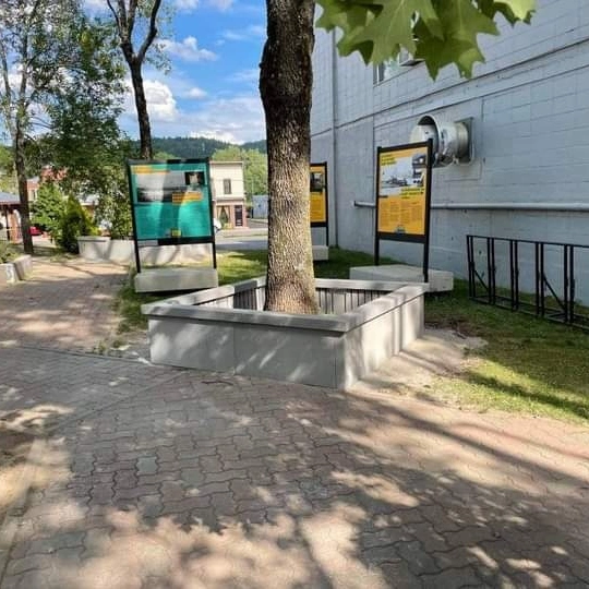 Une passerelle en brique avec un arbre et des panneaux sur le côté d'un bâtiment.