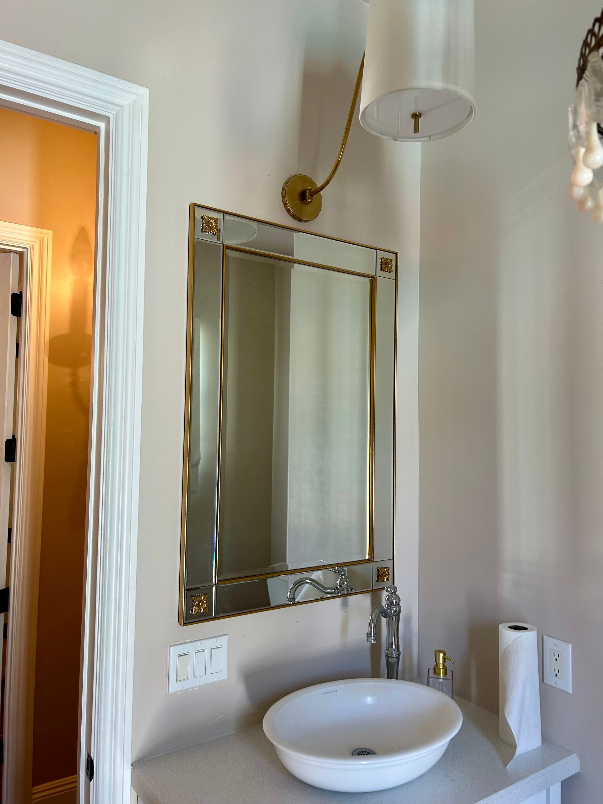 Bathroom with mirror, sink, and sconce lighting. Soft white walls, light fixture.
