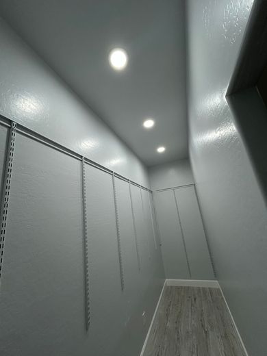 Narrow closet with gray walls, track shelving, and three recessed ceiling lights.
