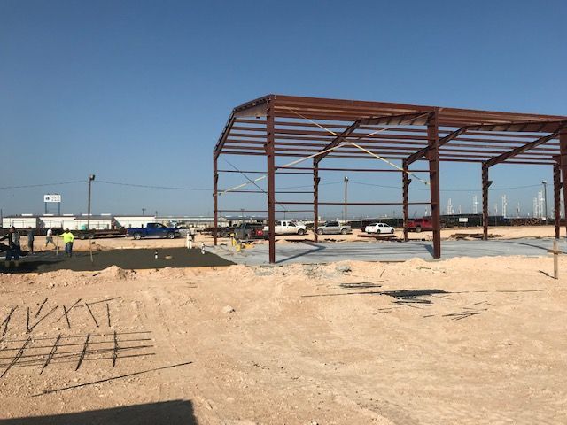 A large metal structure is being built in the middle of a dirt field