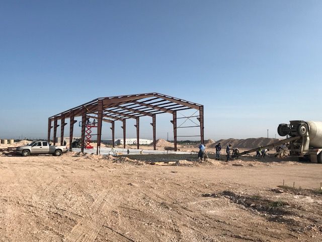 A building is being built in the middle of a dirt field.