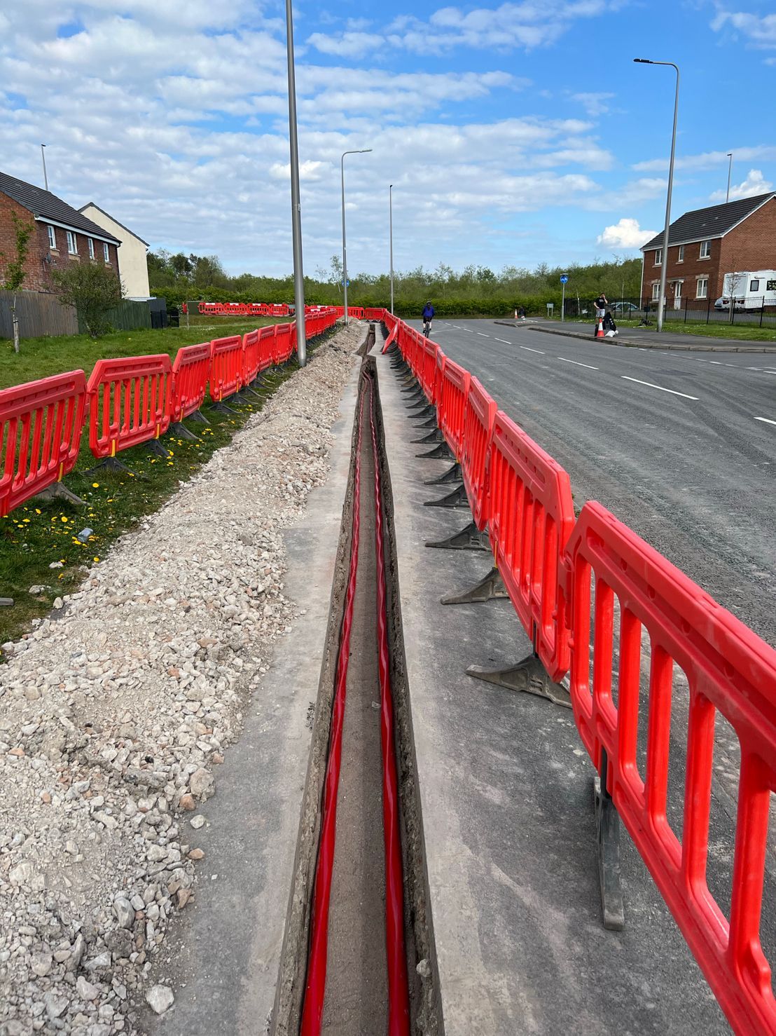 DP Cable Jointing | A red fence surrounds a trench on the side of a road.