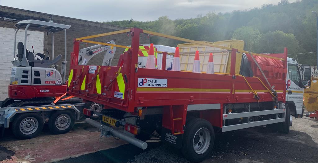 A red truck is parked next to a white truck in a parking lot.