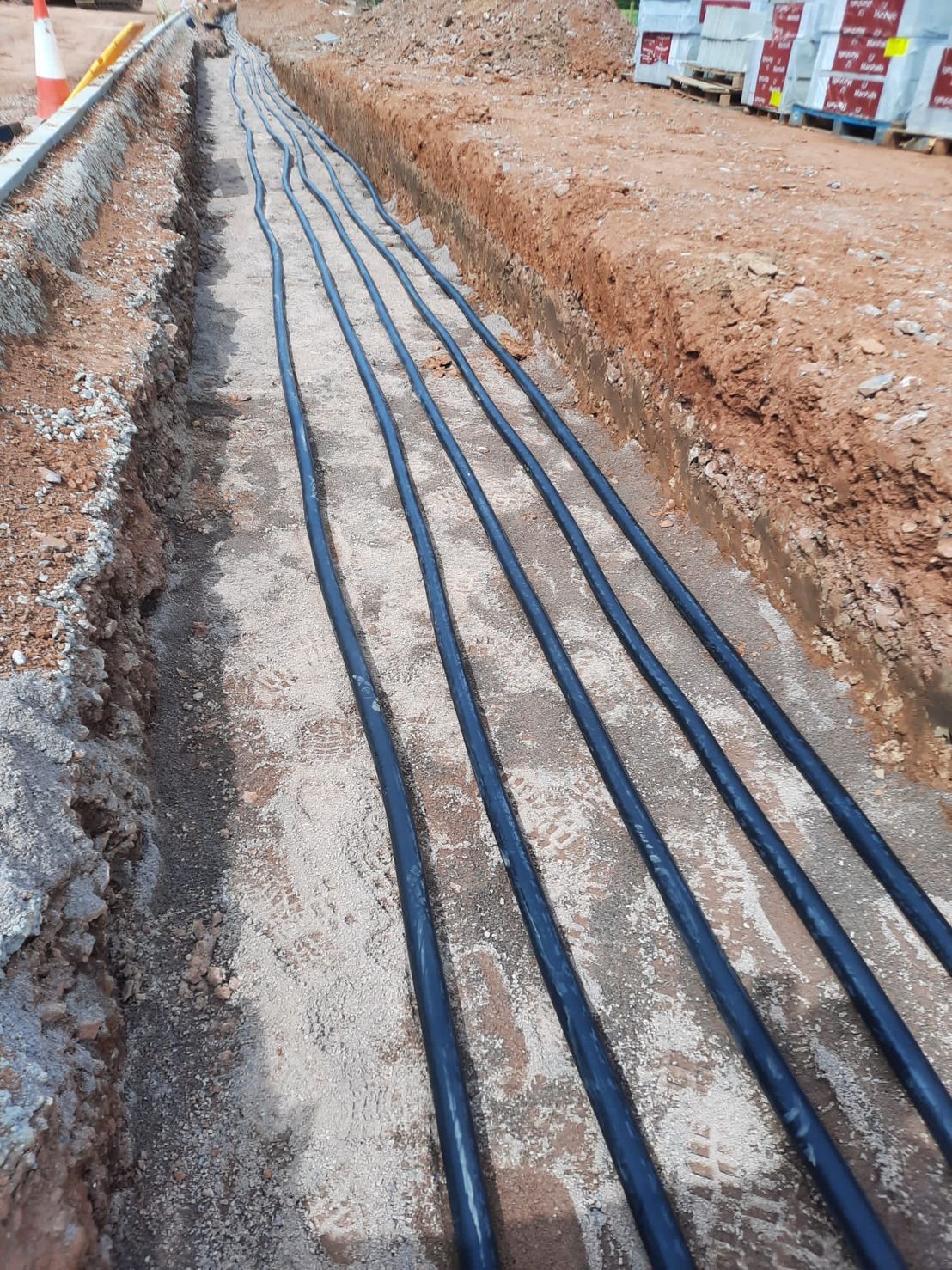 DP Cable Jointing | A bunch of black pipes are laying in the dirt.