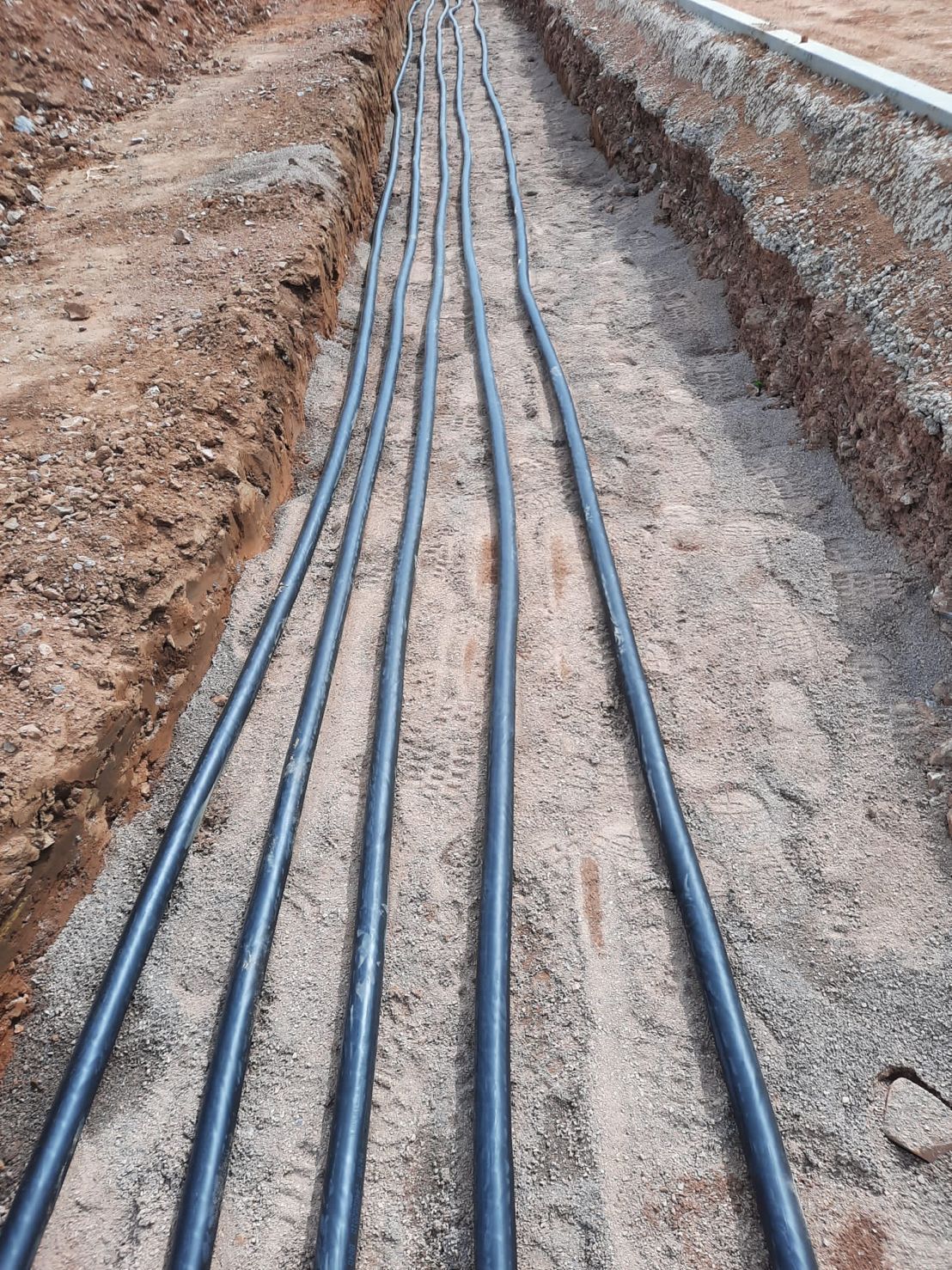 DP Cable Jointing | A bunch of black pipes are laying in the dirt.
