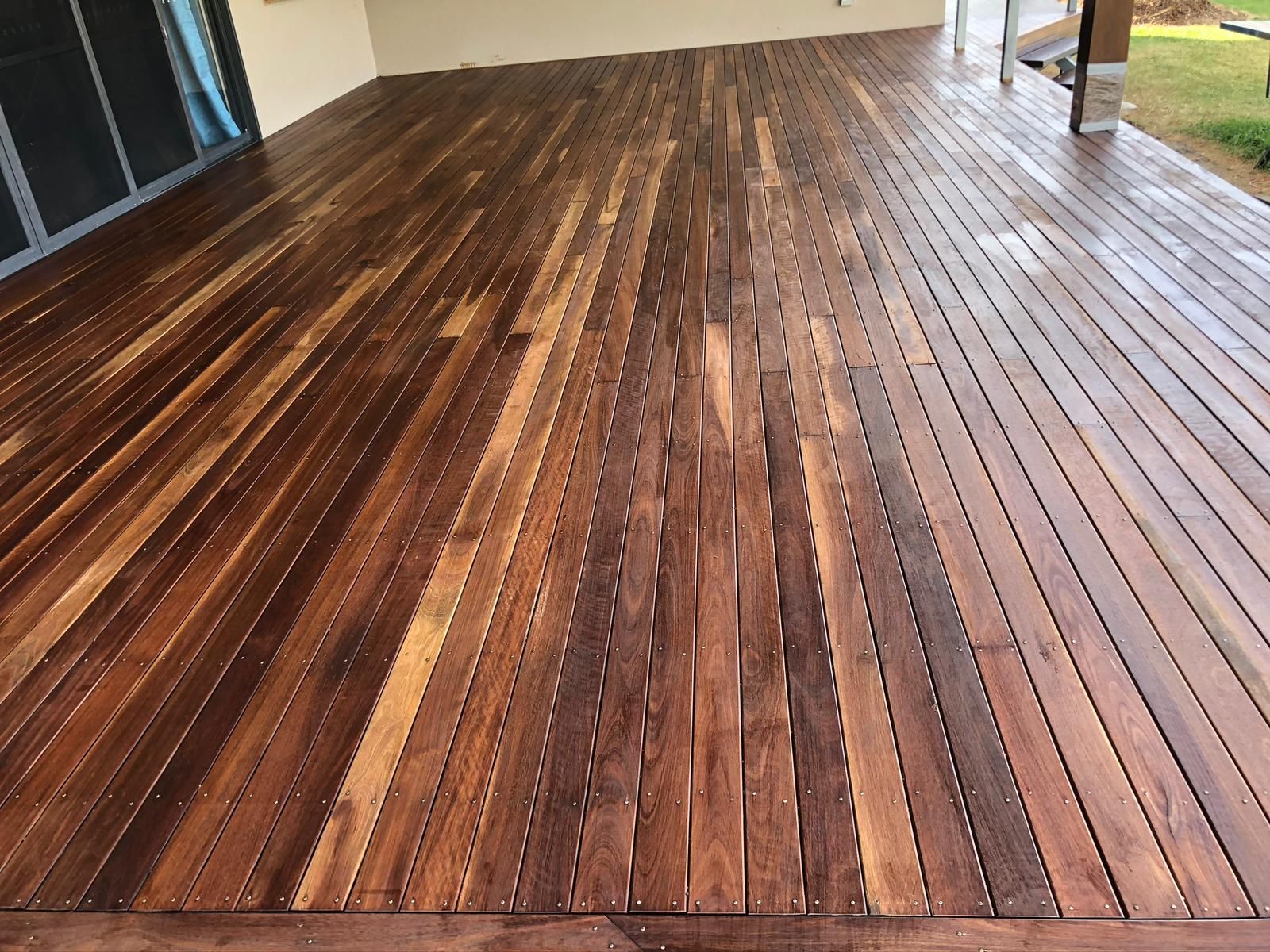 Wooden deck with dark stain, reflecting some light.