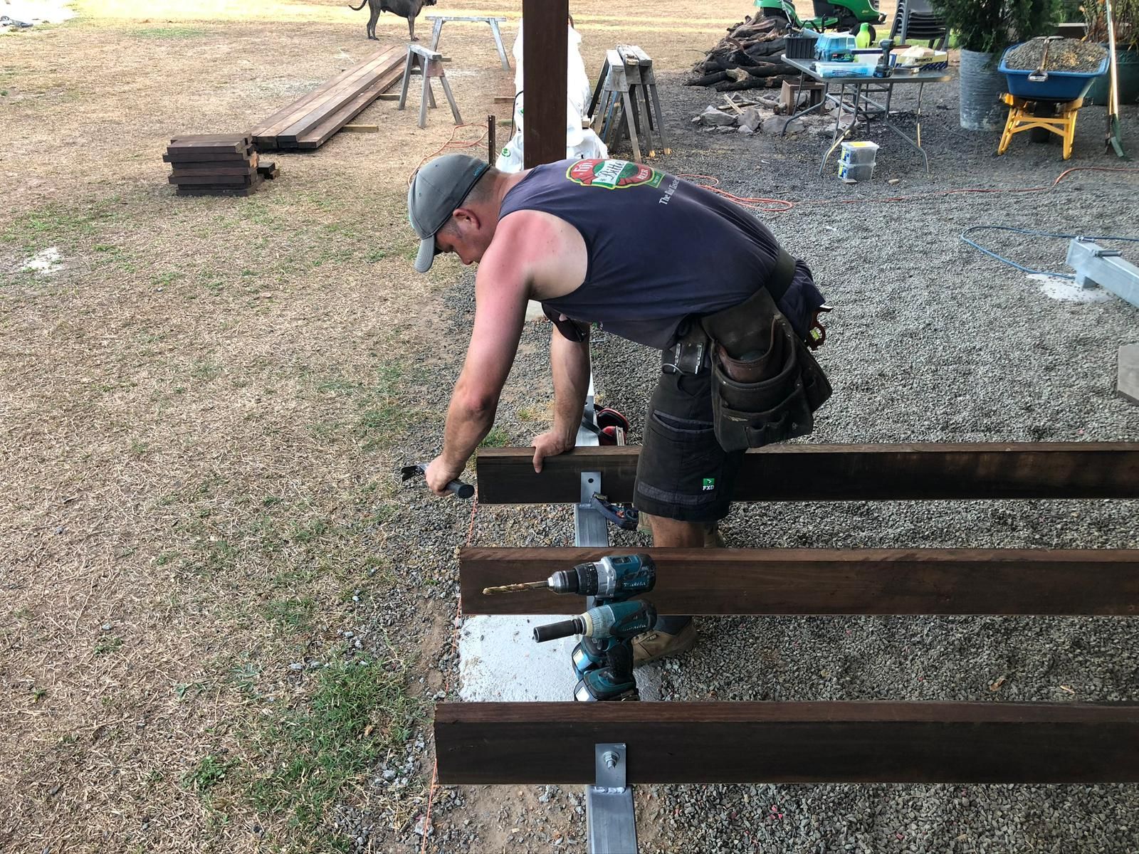 A Person Using a Drill to Attach a Board to a Metal Frame Outdoors — Ericson Constructions in Mareeba, QLD