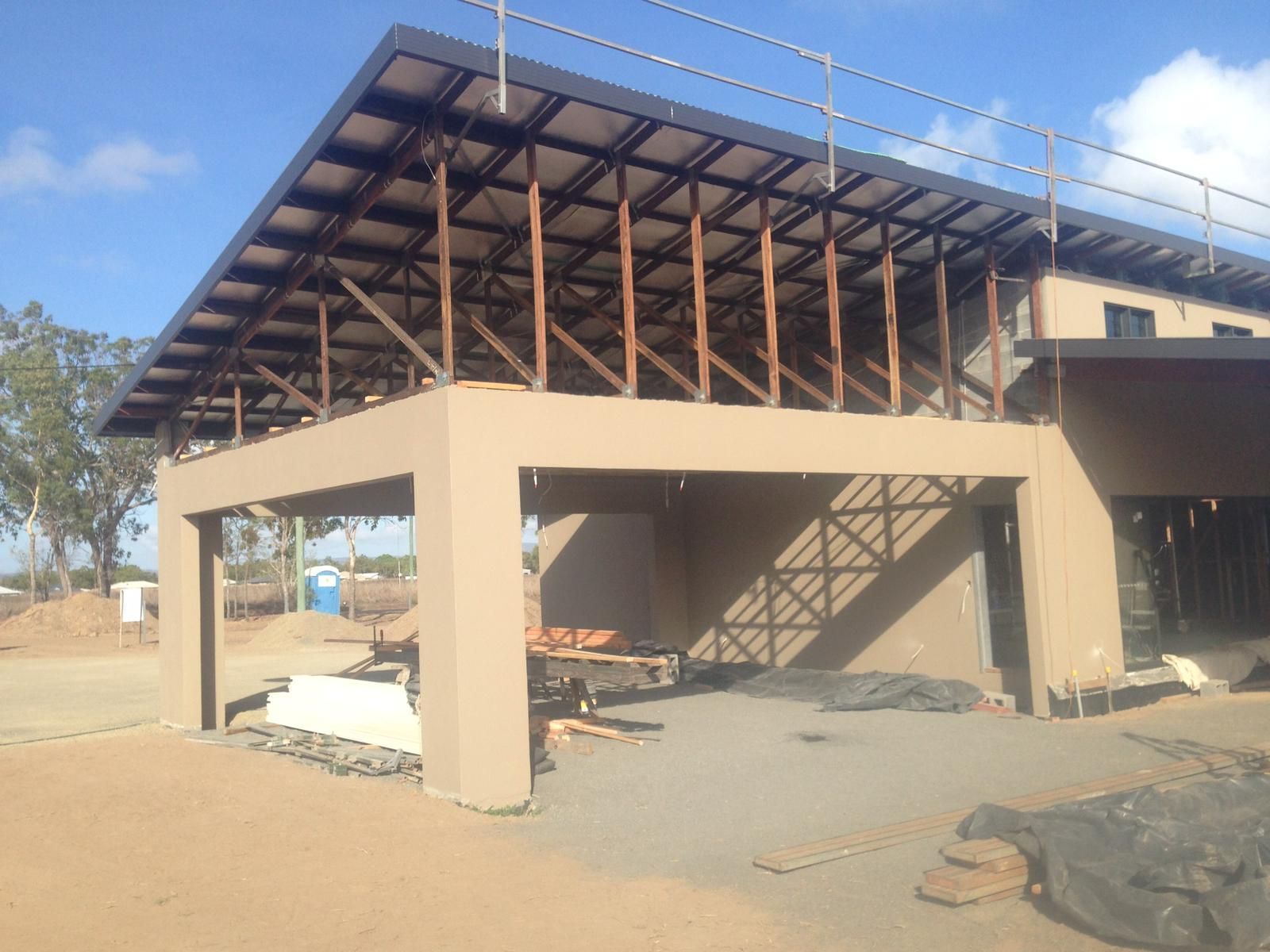 Building under construction with exposed wooden beams, beige walls, and a flat roof.