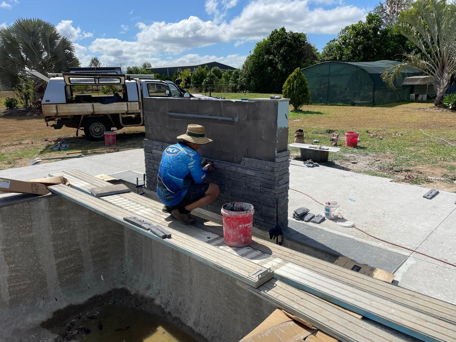 Person Tiling an Outdoor Feature Near a Pool — Ericson Constructions in Mareeba, QLD