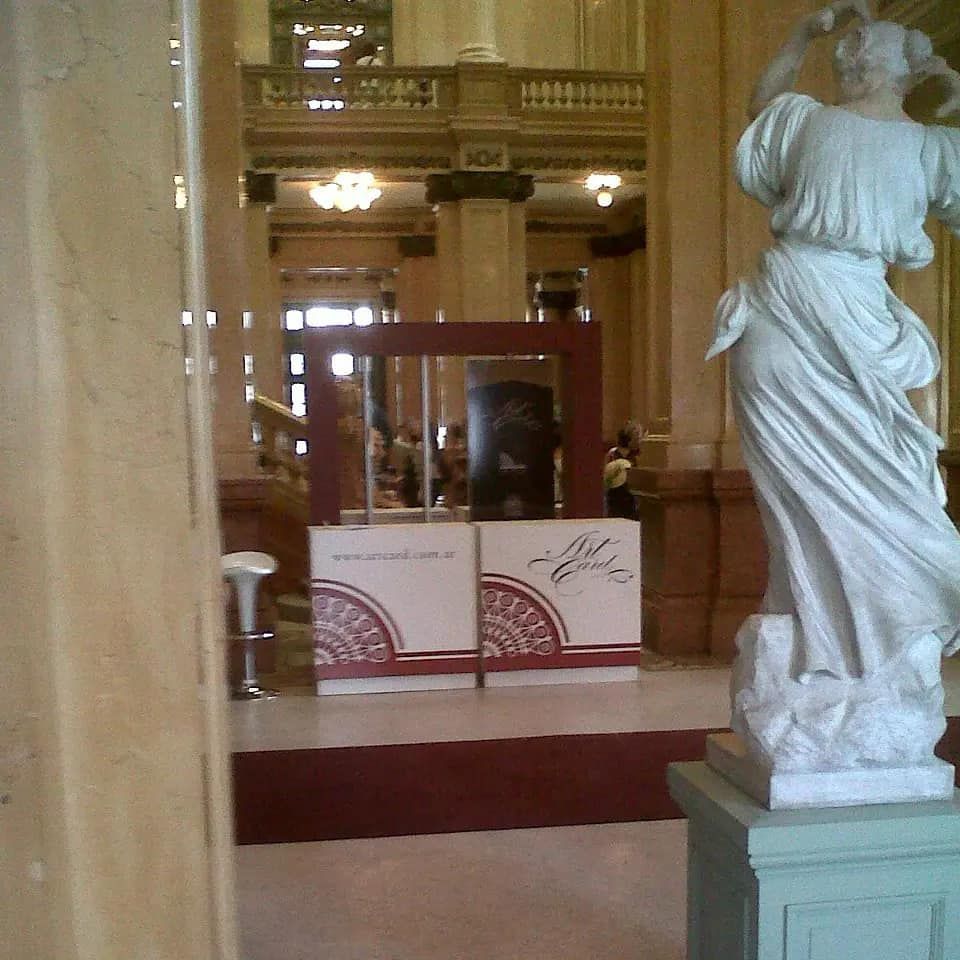 Estatua en un salón interior adornado con una alfombra roja que conduce a un puesto de información.