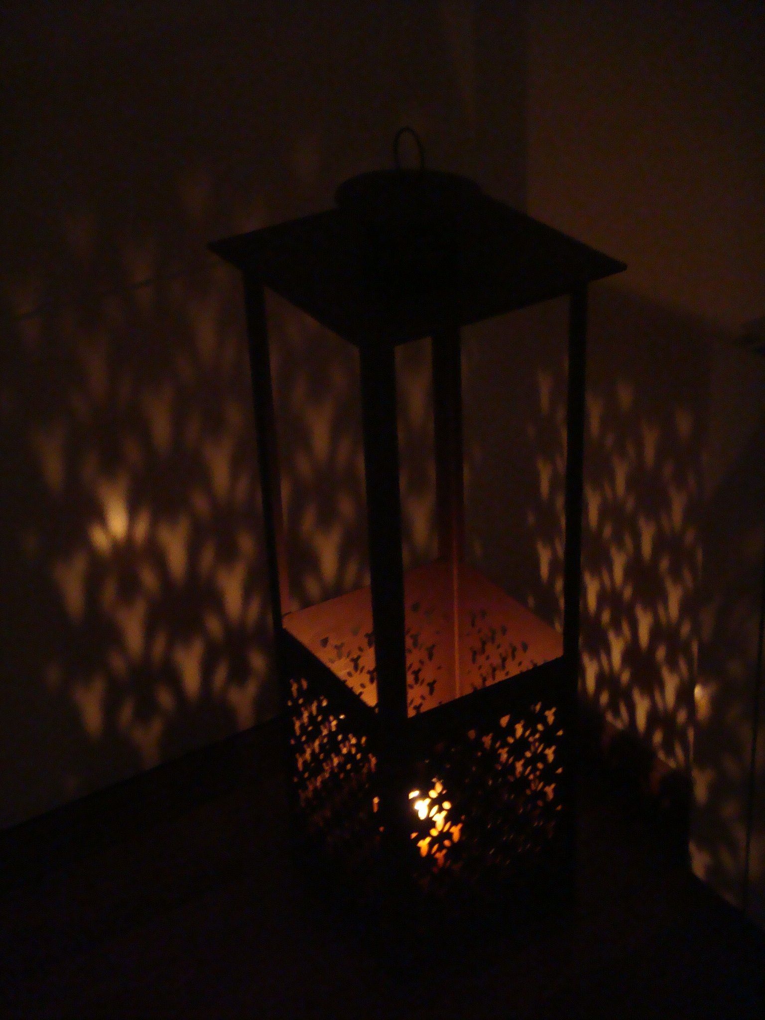 Linterna que proyecta patrones de luz en forma de estrella sobre una pared.