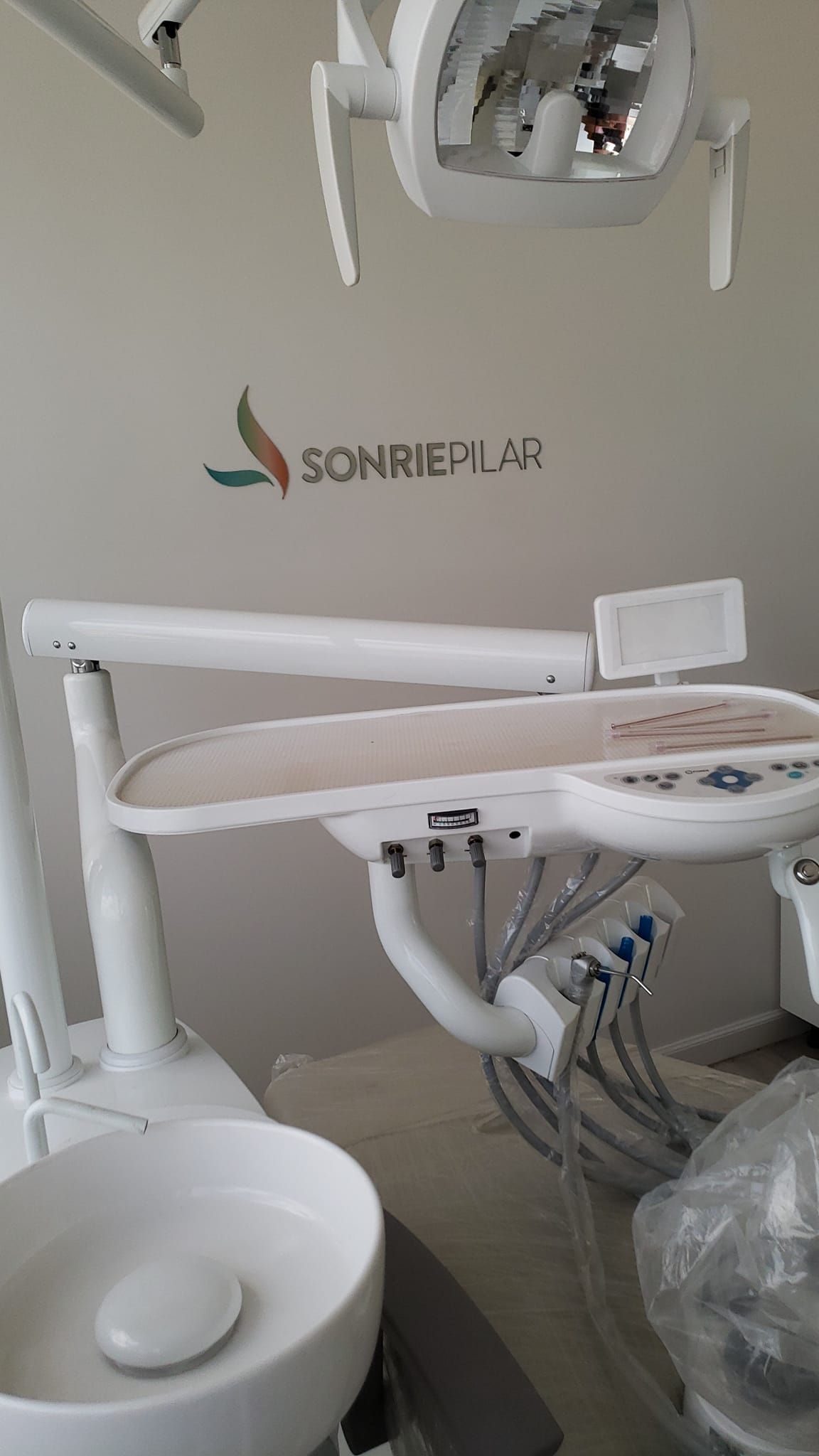 Sillón y equipo dental en una clínica, con el logotipo de SonrieLab visible. Predominan los tonos blanco y plateado.
