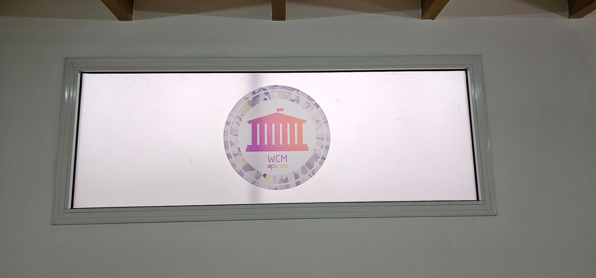 Una ventana rectangular con un logotipo en el medio, enmarcada por una pared blanca.