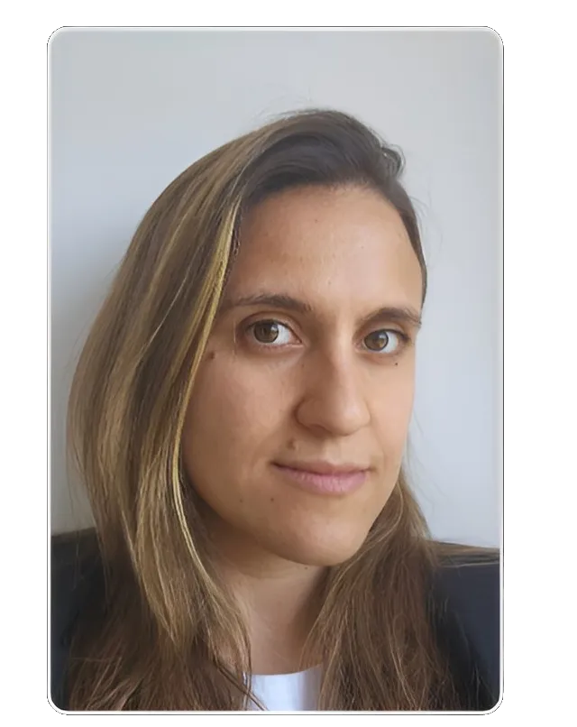 Mujer con cabello largo, mirando a la cámara, vistiendo un blazer, contra una pared de color claro.