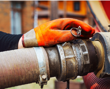 A person wearing orange gloves is working on a hose