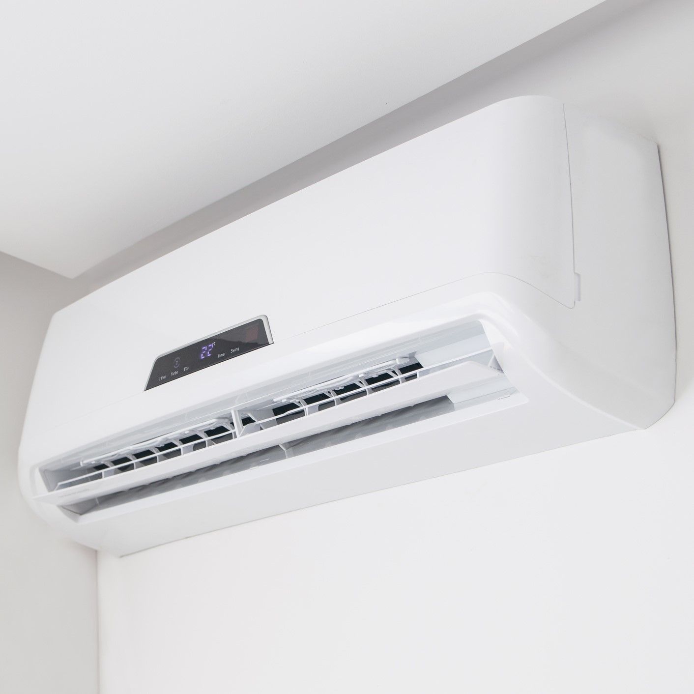 A white air conditioner is hanging from the ceiling in a room.