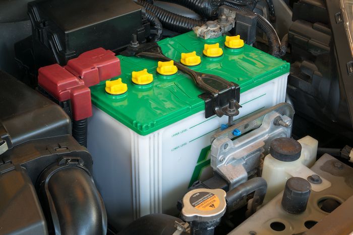 a green battery is sitting under the hood of a car .