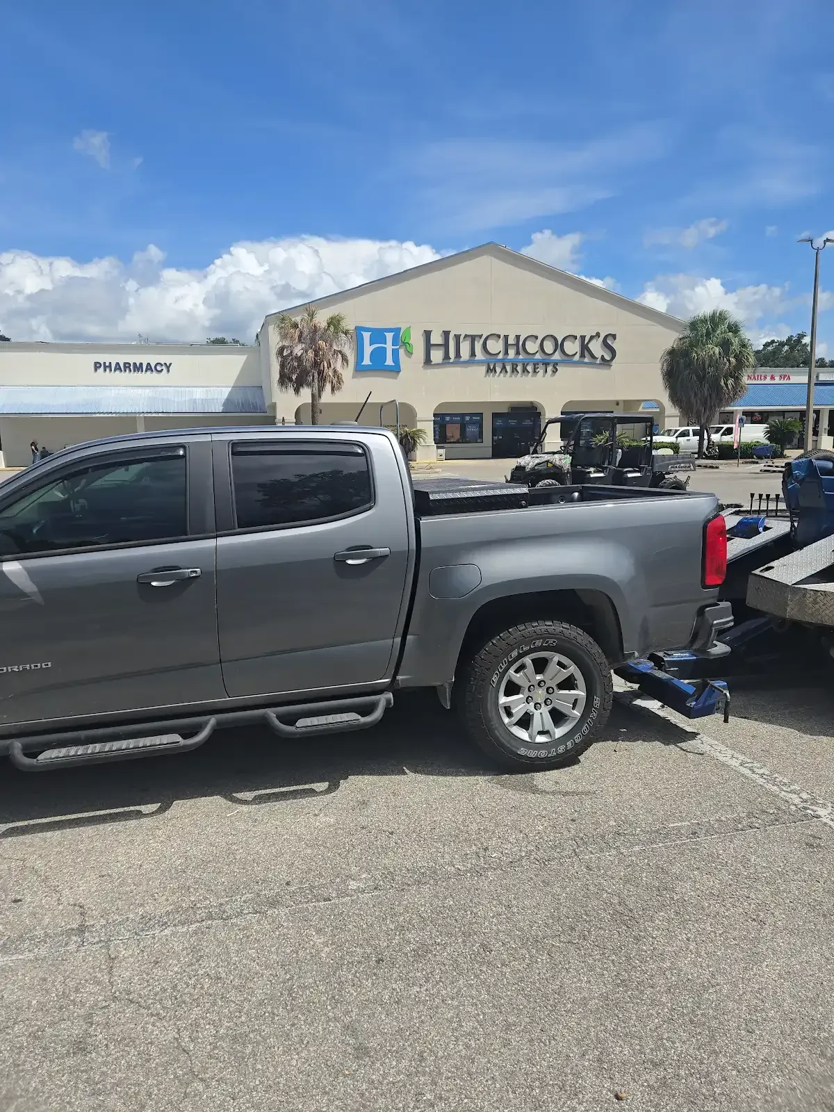 White pickup truck being loaded onto a tow truck by a worker on a sunny day.