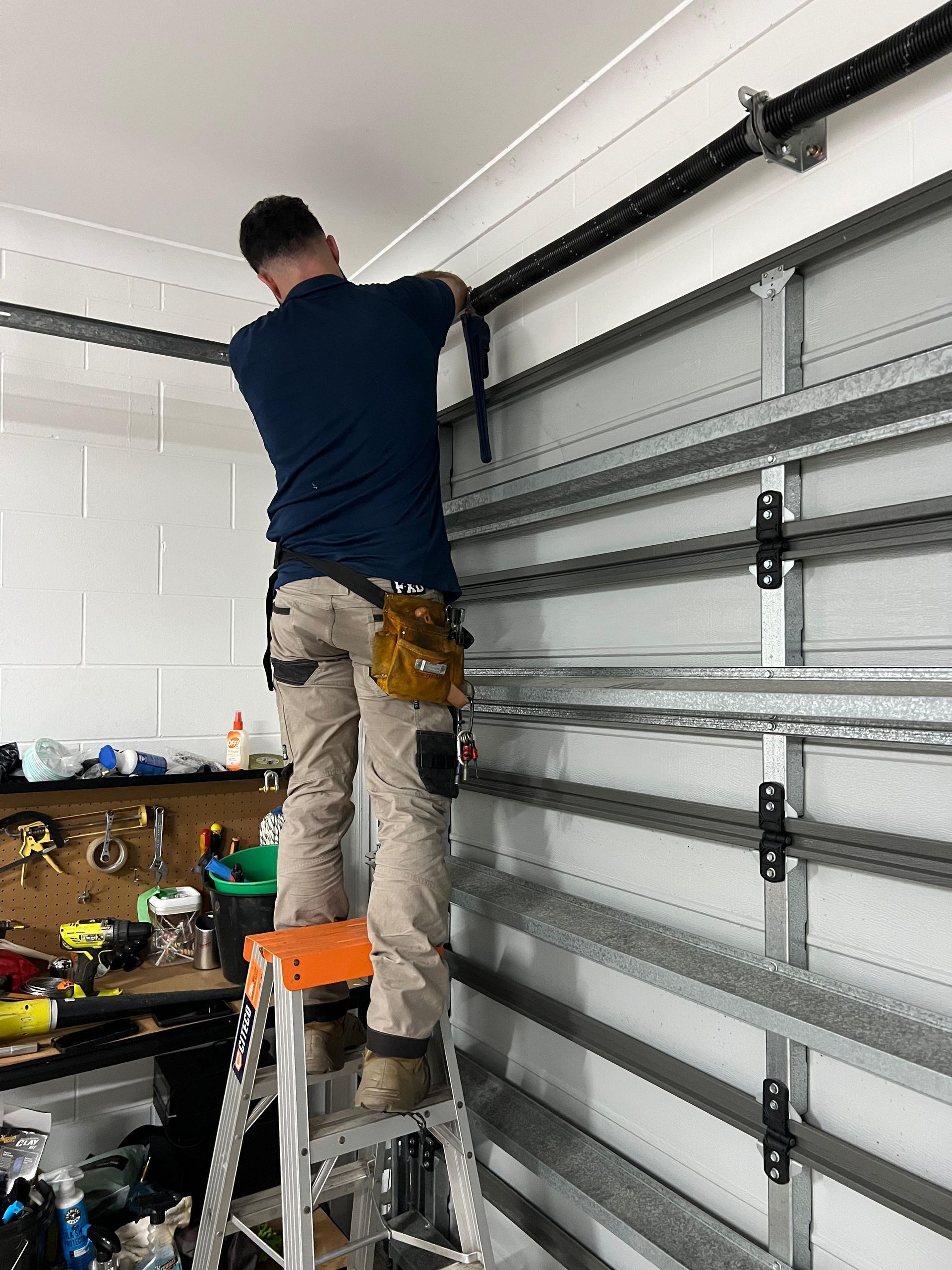 Person standing on a ladder installing a garage door track inside a garage